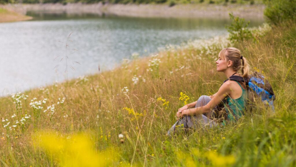 Vrouw zit in de natuur in het gras te genieten