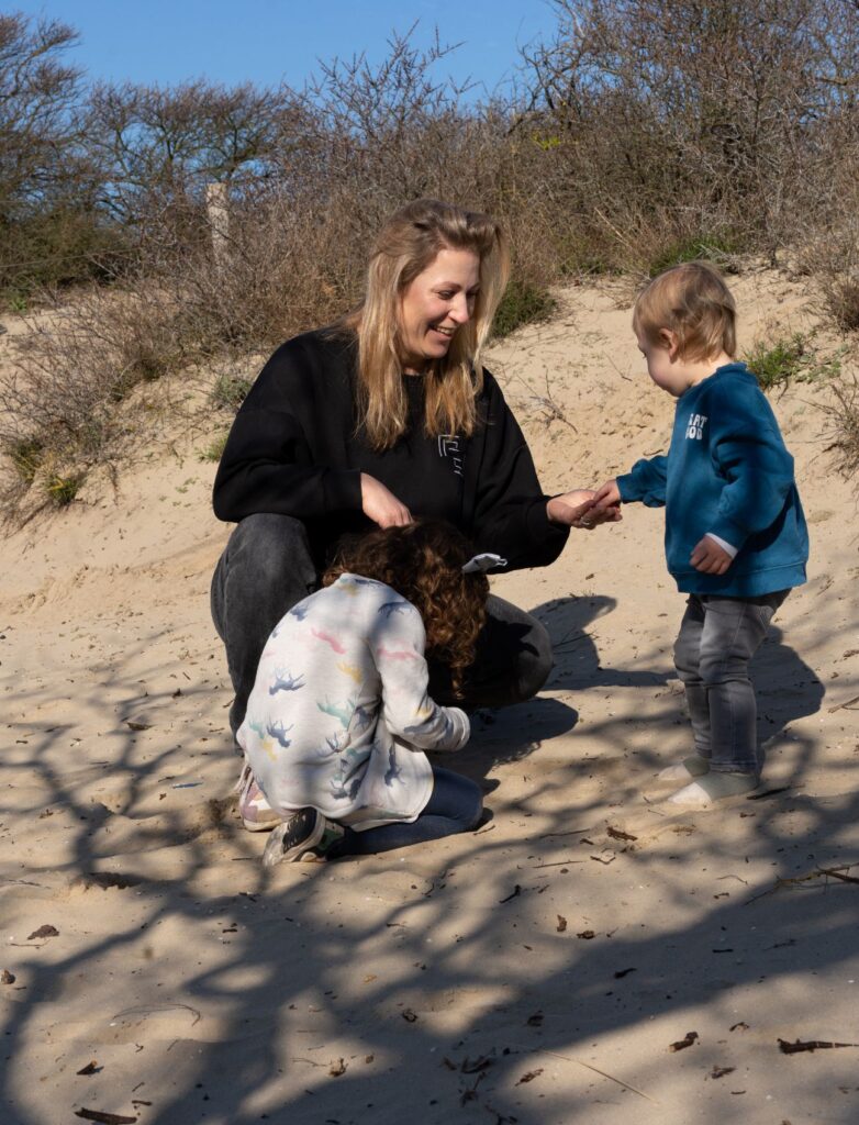 Moeder speelt met kinderen in het zand